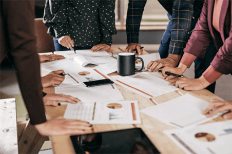 Sales and marketing Group of professionals standing around a table, reviewing documents and analyzing data during a business meeting