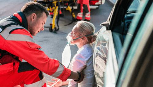 Compensation for car crash injuries - tycoonstory | tycoonstory media Paramedic assisting an injured woman outside a car after an accident.