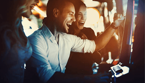 Consider before taking this career path - tycoonstory | tycoonstory media Group of people joyfully playing a slot machine at a casino, smiling and celebrating their gambling experience.