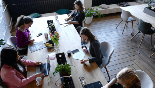 Leadership skills Collaborative team working at a shared workspace with laptops and planners, highlighting teamwork and leadership skills in a productive office setting.