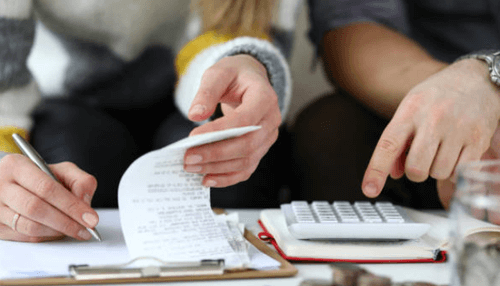 Pertinent fact you need to know about hard money loans - tycoonstory | tycoonstory media Two people working together on financial paperwork, reviewing receipts and using a calculator to manage expenses.