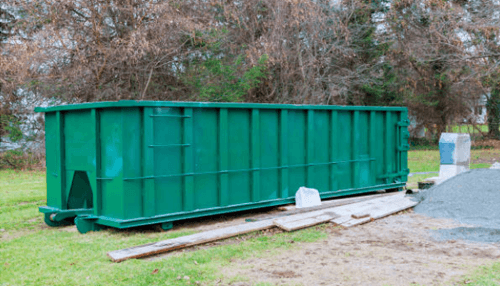 Roll-off dumpsters Green roll-off dumpsters placed outdoors for residential or commercial waste removal.