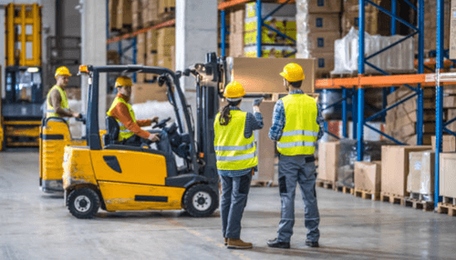 Warehousing facilities Warehouse staff and a forklift operator moving goods in an industrial storage facility.