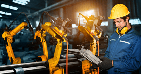 Advantages of robotic welding-tycoonstory | tycoonstory media Factory technician monitoring automated robotic welding machines with robotic arms operating on a production line.