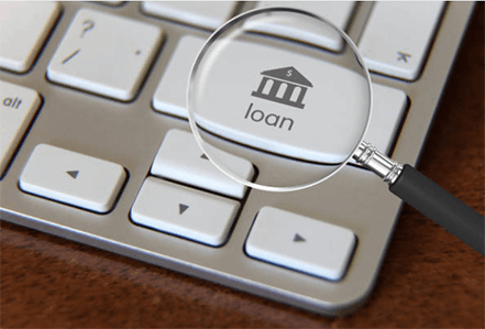 Bank loan-tycoonstory | tycoonstory media A magnifying glass focused on the'loan' key on a keyboard, symbolizing the process of researching loans and debt management.