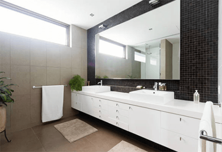 Bathroom space-tycoonstory | tycoonstory media Modern bathroom interior with a sleek white bathroom vanity, double sinks, large wall mirror, minimal decor, and contemporary lighting.