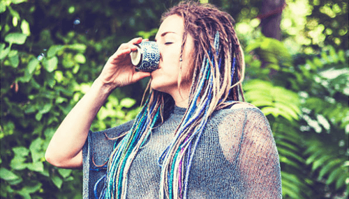 Busted for ayahuasca Woman outdoors drinking from a small cup in a natural setting, representing mindfulness, altered states, and modern cultural discussions around dmt experiences.
