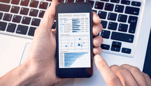 5 reasons why companies should start price monitoring - tycoonstory | tycoonstory media Person holding a smartphone displaying business analytics and data trends for online gambling price monitoring.