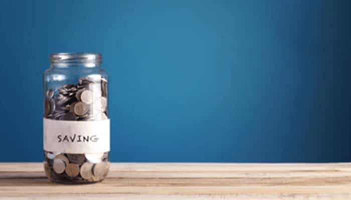 Bhhh | tycoonstory media Saving money idea illustrated by a glass jar filled with coins, symbolizing personal savings goals, financial discipline, and future security.