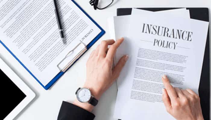 Business insurance | tycoonstory media Reviewing an insurance policy document for legal and financial protection while setting up a new business.