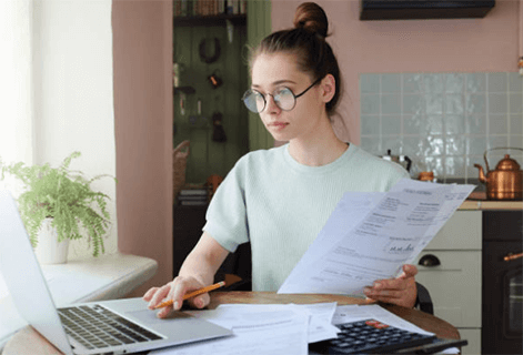 Lowering electricity bills-tycoonstory | tycoonstory media Woman reviewing her bills and expenses on a laptop, managing her electricity bills and finances at home