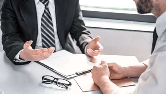 Nynb h | tycoonstory media Car accident attorney consulting with a client at a desk to discuss injury claims and legal options.
