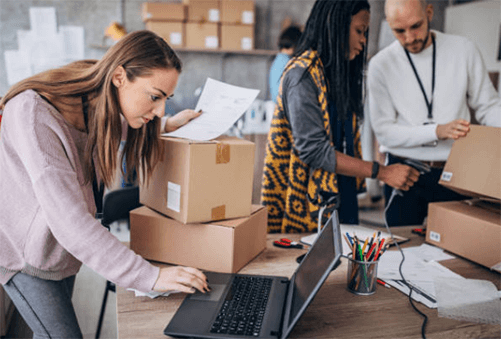 Techniques for dropshipping-tycoonstory | tycoonstory media E-commerce team managing online orders, packaging products, and updating inventory using a laptop in a warehouse workspace