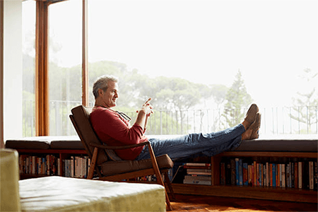 Benefits of starting a new business in switzerland-tycoonstory | tycoonstory media A man relaxing in a cozy home in switzerland, enjoying the view from a large window with a peaceful ambiance.