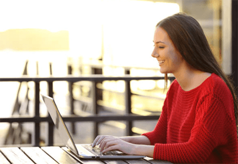 Ways to increase website traffic guest blogging-tycoonstory | tycoonstory media A woman working on a laptop outdoors, symbolizing content creation and online engagement to increase traffic to your website.