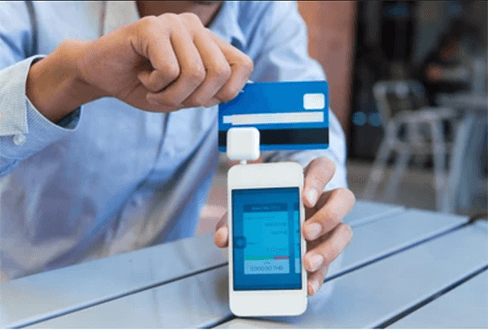 Mobile pos system Image of a person using a mobile pos system by swiping a credit card through a card reader attached to a smartphone, demonstrating a mobile point-of-sale transaction.