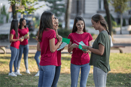 Distribution of flyers for your businesses in paris-tycoonstory | tycoonstory media Group of young people exchanging flyers in a park, demonstrating how flyers for your businesses can be used for local promotion and outreach.