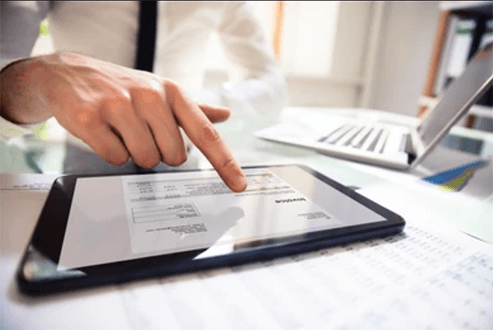 How debt collection software works-tycoonstory | tycoonstory media A close-up of a person reviewing an invoice on a tablet, highlighting the digital management of debt collection.