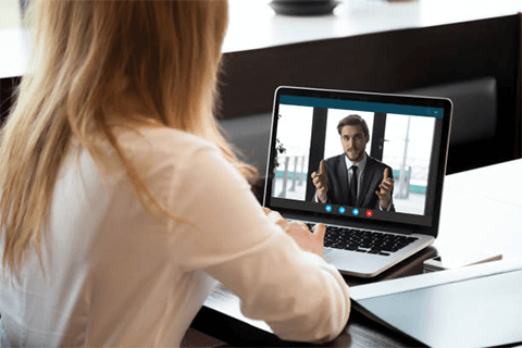 How to engage remote employees-tycoonstory | tycoonstory media A woman participating in a video conference on her laptop with a colleague, illustrating the experience of working remotely and virtual communication.