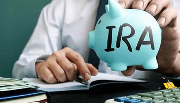 Piggy bank | tycoonstory media A person holding a piggy bank labeled ira individual retirement account, emphasizing savings and financial planning for retirement