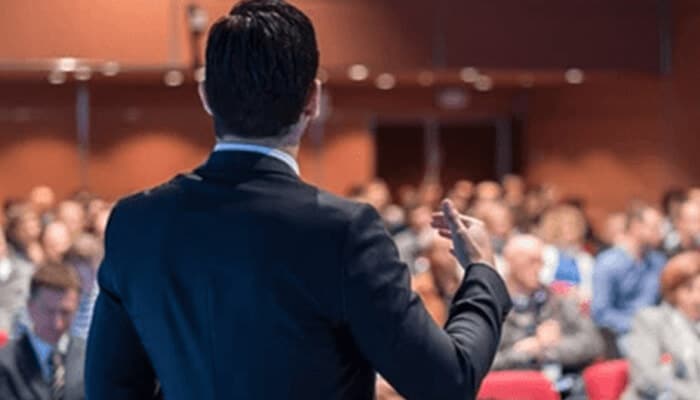 Become an expert | tycoonstory media Entrepreneur presenting to a large audience, showcasing the role of effective communication and presentation in the creative process in entrepreneurship.