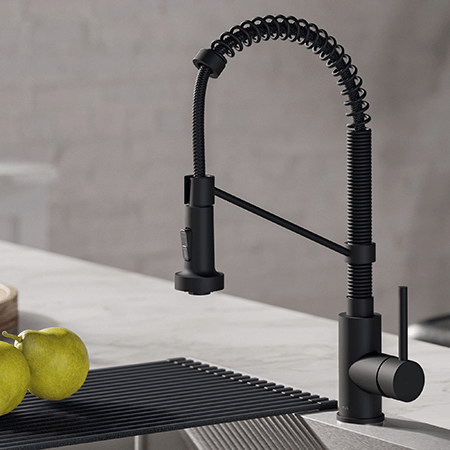 Kitchen faucet in brushed gold-tycoonstory | tycoonstory media Black modern kitchen faucet installed over a sink with terrazzo countertop, showcasing a sleek and functional kitchen design.
