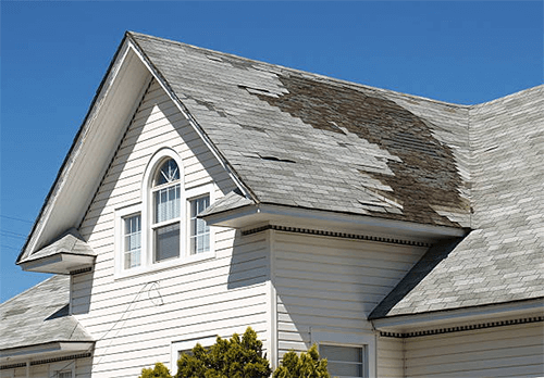 Rusting roof-tycoonstory | tycoonstory media A worn house roof with missing shingles in need of inspection by experienced roof contractors.