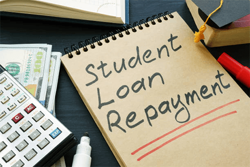 Student loan repayment strategy-tycoonstory | tycoonstory media Notebook with student loan repayment written on the cover, surrounded by financial tools, highlighting the importance of managing student debt.