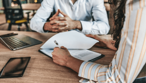 Financing business - tycoonstory | tycoonstory media Two people discussing paperwork, representing the decision-making process between hard money loans vs. Soft money loans for real estate investments.