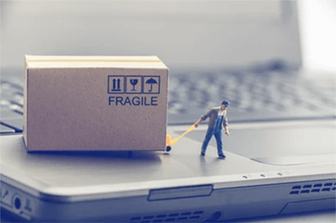 How to find a wholesale distributor-tycoonstory | tycoonstory media A miniature figure pulling a fragile package on top of a laptop, symbolizing the process of logistics and delivery when you find a wholesale distributor.