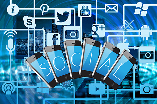 Social media Multiple smartphones with the word ‘social’ surrounded by digital social media icons, highlighting online marketing trends.