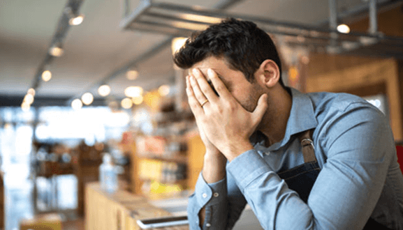 Lack of planning A stressed worker sitting with his head in his hands, representing financial and operational struggles common in startup businesses.
