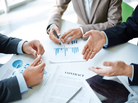 Construction project Construction project meeting showing professionals reviewing contracts, charts, and financial plans at a work table.