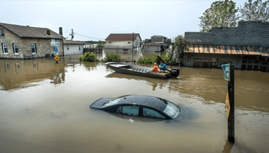 Floods Natural disasters flood scene with submerged cars, flooded houses, and people navigating the water in a small boat in a heavily inundated residential area.