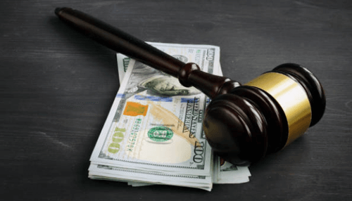 Hire bail bond - tycoonstory | tycoonstory media Judge’s gavel resting on cash, symbolizing the financial process involved in securing a bail bond.