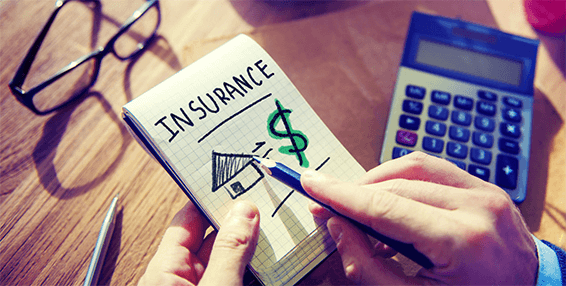 Insurance-tycoonstory | tycoonstory media Person drawing insurance symbols on a notepad with a calculator nearby, illustrating the importance of small business insurance for financial protection.