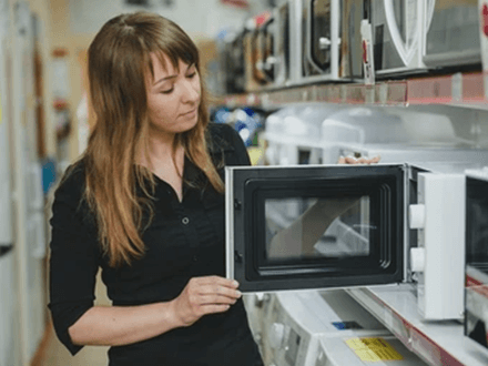 Lg microwave oven Customer inspecting an lg microwave oven in a store, checking its features and build quality.