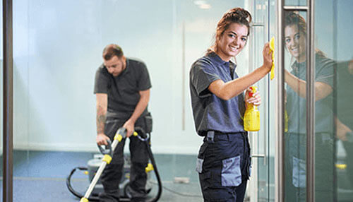 Choosing best commercial cleaners in sydney Commercial cleaners wiping glass surfaces and vacuuming an office space during professional cleaning service.