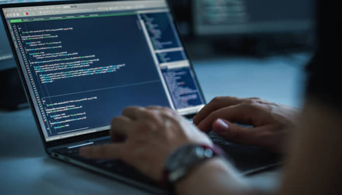 Developer A person sits at a laptop, with highlighted lines of code in a dimly lit space to become a developer.