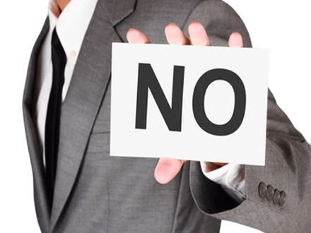 Know to say no A businessperson holding a large sign that says'NO,' symbolizing the importance of setting boundaries and saying no in professional settings.