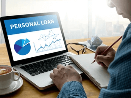 Personal loans - tycoonstory | tycoonstory media Person taking notes while viewing personal loan data and charts on a laptop, representing loan planning and analysis.