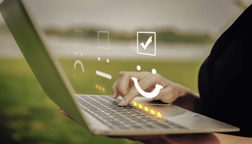 Feedback A person using a laptop to submit a feedback form with smiley and star rating icons, symbolizing customer satisfaction and reviews.