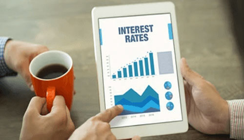 Interest rate A person examining interest rates and debt schedule data on a tablet, with a cup of coffee, analyzing financial trends and charts.