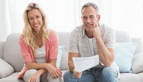 Parent loans Happy couple on a sofa holding paperwork. Discussing financial aid options like parent loans.