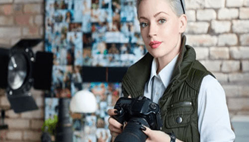 Photographer Young professional holding a camera in a creative studio environment, representing photography and media-related startup ideas in the digital content and creative industry.