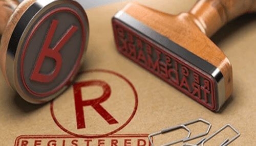Register your business name and trademark A set of trademark stamps rests on a desk, emphasizing legal branding procedures where an llc often requires registered marks.