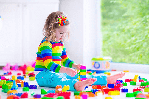 Colorful plastics toys Young child sitting by a window and exploring a bright lock and key toy, developing fine motor skills and early learning through play.