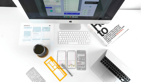 Determine the target market Workspace with computer, sketches, and mobile wireframes showing the design process for planning and developing digital products.