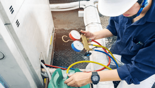 Hvac services Hvac technician inspecting and servicing an outdoor air conditioning unit using pressure gauges and tools, illustrating professional hvac maintenance and repair services.