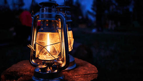 Lighting from all sides Camping lamp glowing at night with 360-degree lighting from all sides, placed outdoors to provide warm illumination for nighttime camping and outdoor activities.